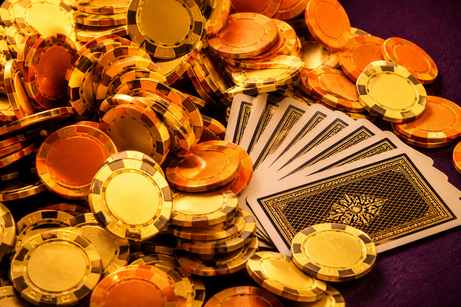Goldene und orange Casino-Jetons und aufgefächerte Spielkarten auf dunklem Filz — Symbolbild zum Dragonia Casino Bonus